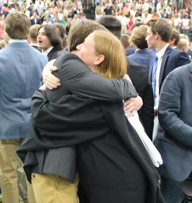 Campus Minister Mrs. Mary Emrich, who offered words of advice to the Class of 2019, receives a hug during the Sign of Peace. 