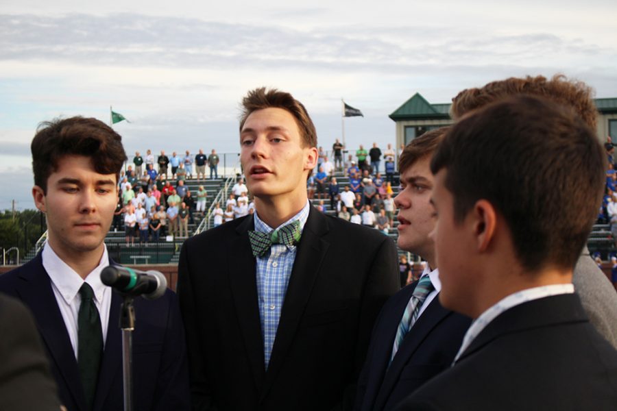 Trinity senior Eric Gallehr-Miracle, center, and other Trinity Singers perform before a Rocks football game. 